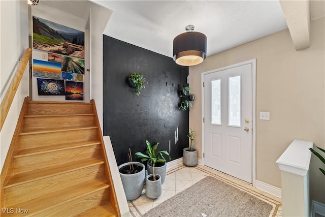 tiled foyer entrance featuring stairs and baseboards