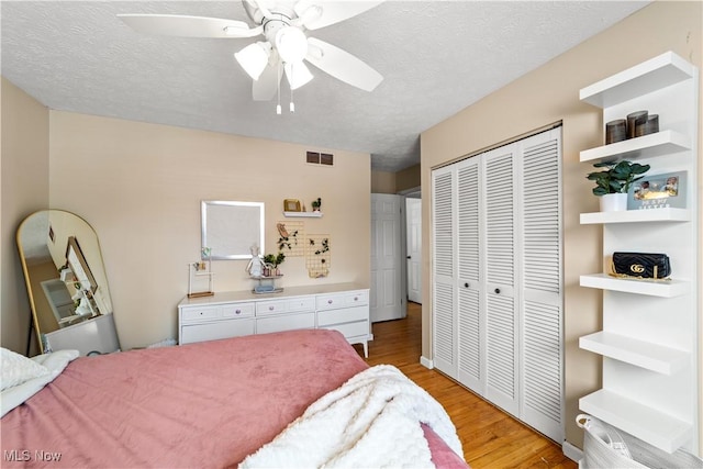 bedroom with a closet, visible vents, light wood-style flooring, and a textured ceiling