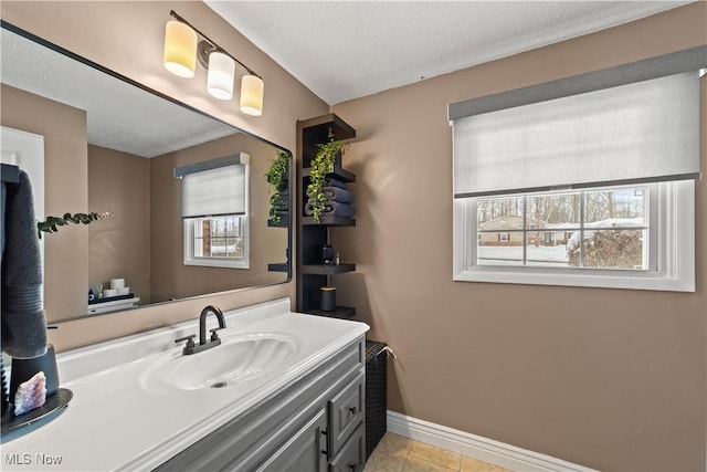 bathroom featuring a textured ceiling, vanity, baseboards, and tile patterned floors