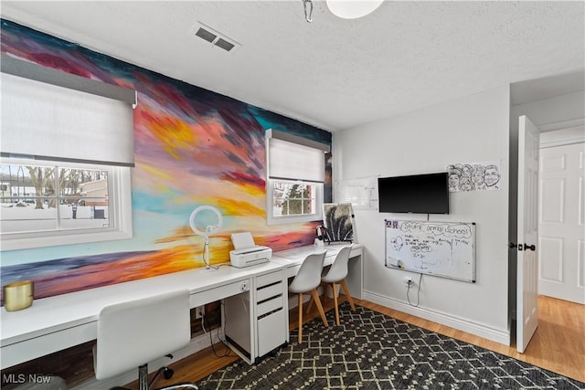 office with baseboards, a textured ceiling, visible vents, and dark wood-style flooring