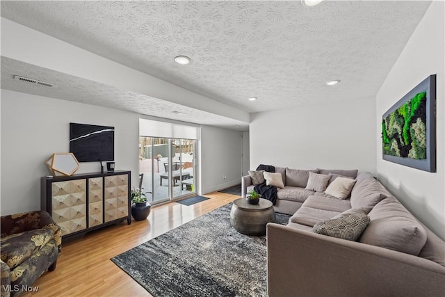 living room with recessed lighting, visible vents, a textured ceiling, wood finished floors, and baseboards