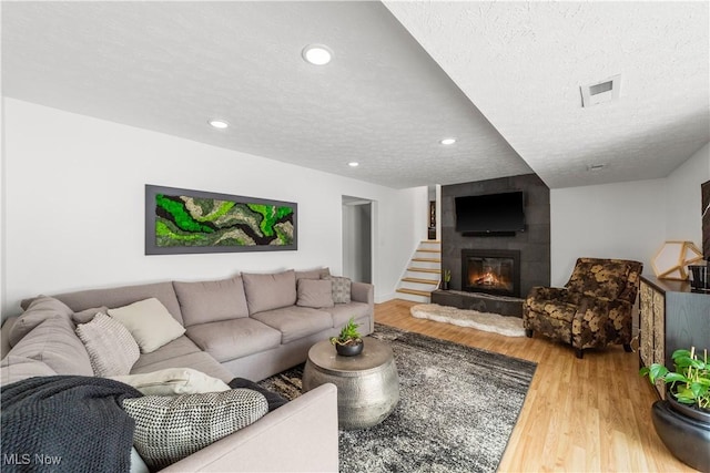 living room with a textured ceiling, recessed lighting, a fireplace, wood finished floors, and visible vents