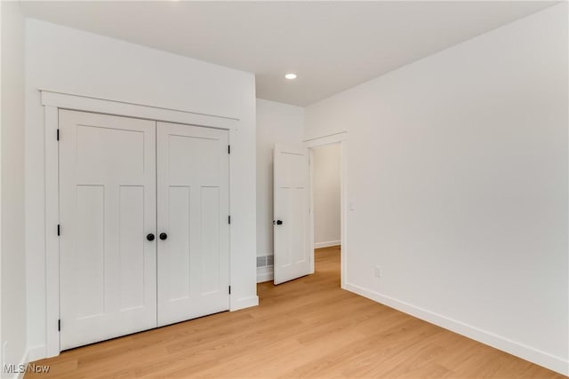 unfurnished bedroom with light wood-style floors, baseboards, a closet, and recessed lighting