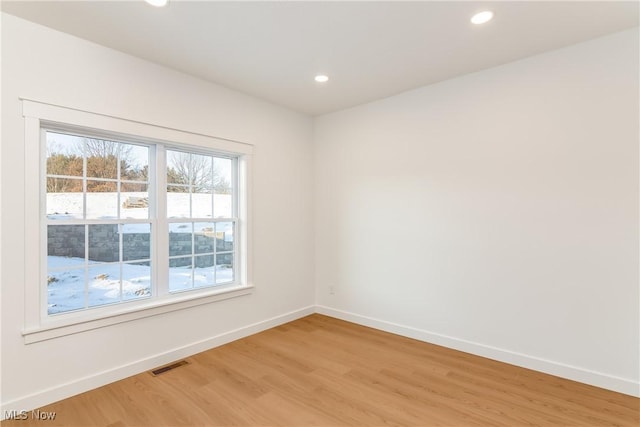 unfurnished room with recessed lighting, light wood-type flooring, visible vents, and baseboards