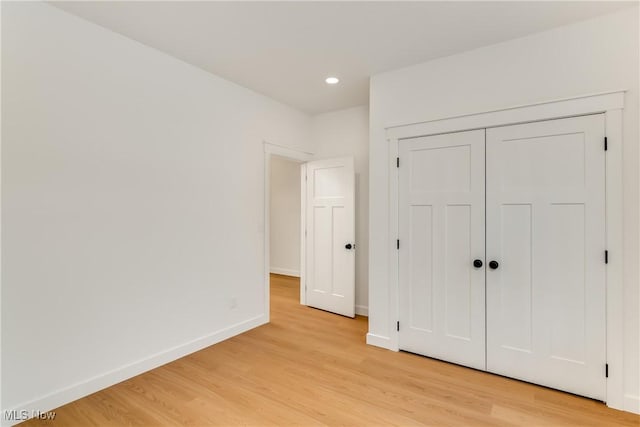 unfurnished bedroom with light wood-style floors, a closet, recessed lighting, and baseboards