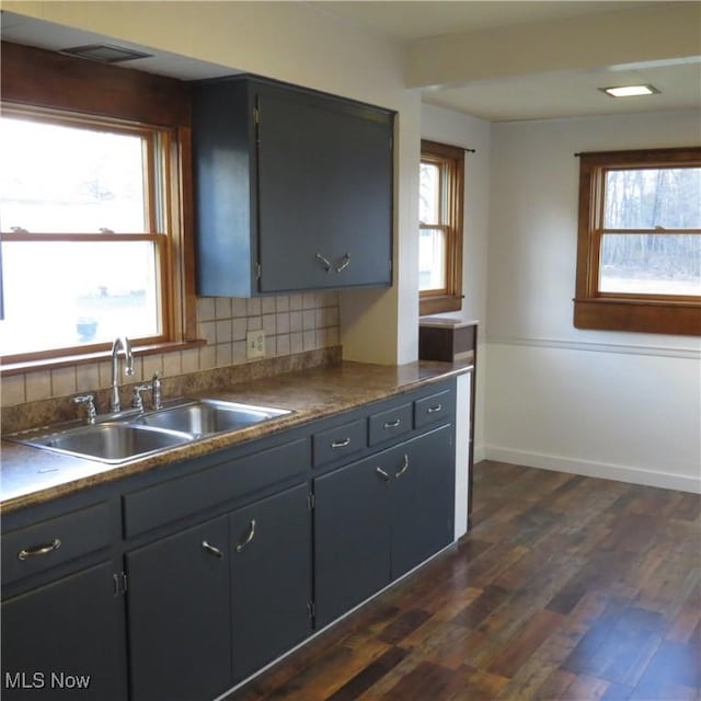 kitchen featuring a healthy amount of sunlight, dark wood-style floors, backsplash, and a sink