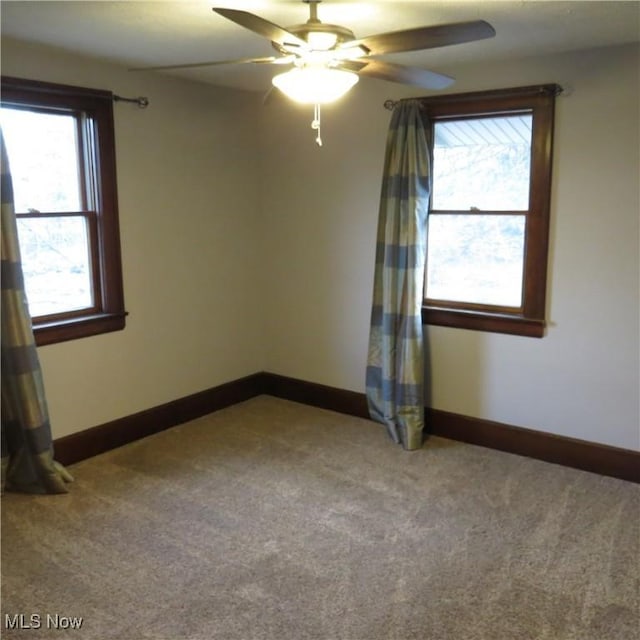 carpeted spare room with baseboards and a ceiling fan