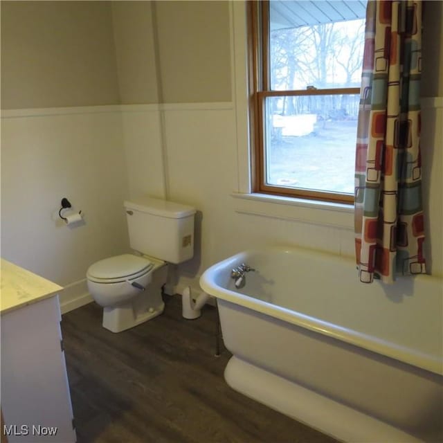 bathroom featuring vanity, a freestanding tub, wood finished floors, and toilet