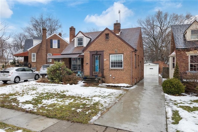 view of front of property featuring an outbuilding, brick siding, a chimney, and a garage