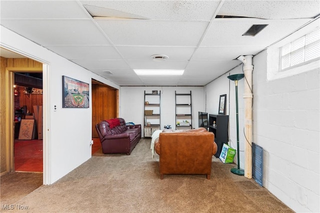 carpeted home office with concrete block wall and a paneled ceiling