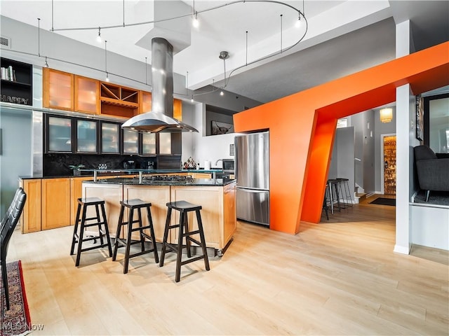 kitchen with island range hood, decorative backsplash, dark countertops, a kitchen island, and stainless steel appliances