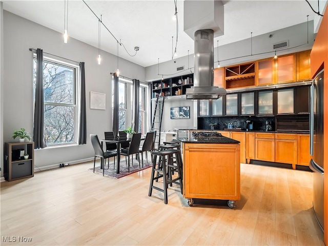 kitchen featuring tasteful backsplash, visible vents, a kitchen island, island exhaust hood, and light wood-style floors