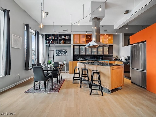 kitchen with island range hood, a kitchen island, black dishwasher, freestanding refrigerator, and dark countertops