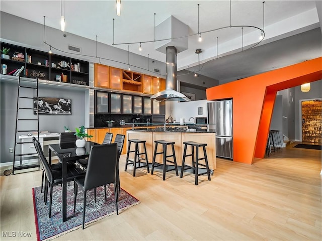 dining space with light wood-style floors, a high ceiling, visible vents, and rail lighting