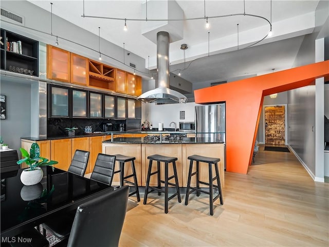 kitchen with visible vents, island range hood, dark countertops, stainless steel appliances, and light wood-style floors