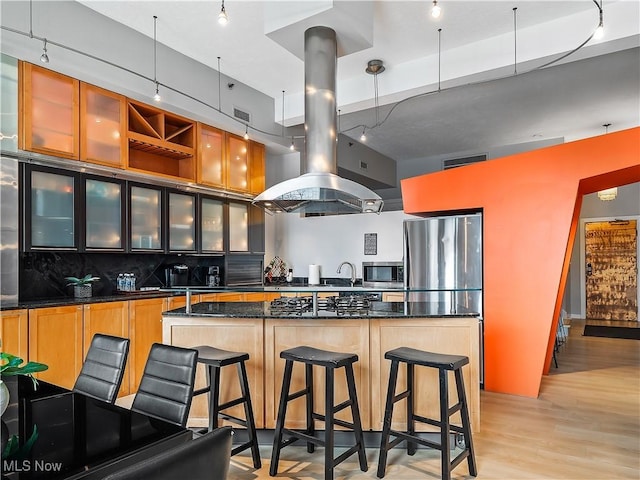 kitchen featuring visible vents, island range hood, light wood-style flooring, a center island, and stainless steel appliances