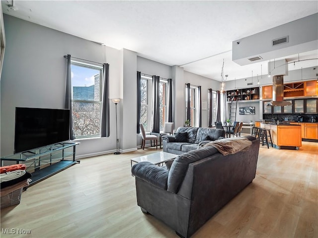 living room featuring light wood finished floors, visible vents, and baseboards