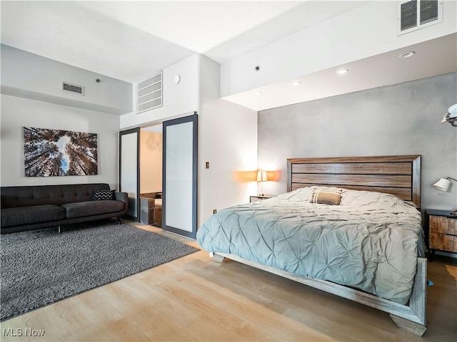 bedroom featuring a towering ceiling, visible vents, and wood finished floors