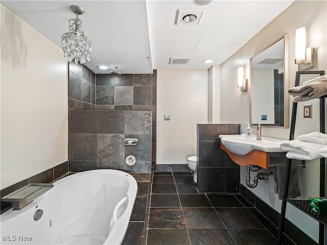 bathroom featuring a whirlpool tub, a sink, visible vents, and toilet