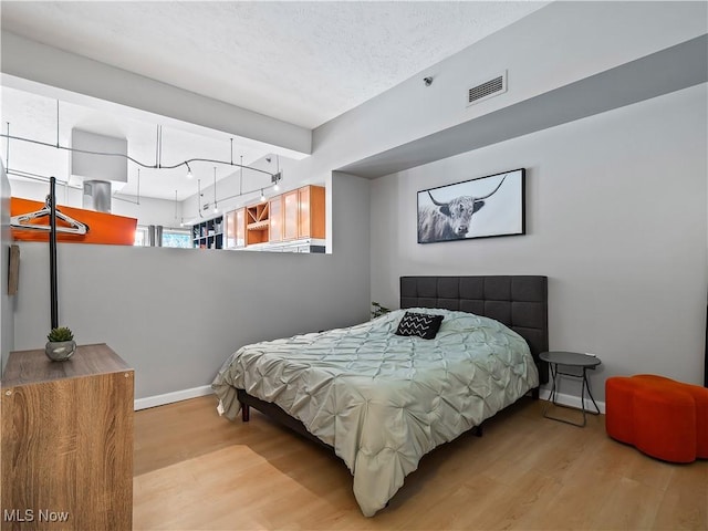 bedroom with visible vents, baseboards, and wood finished floors