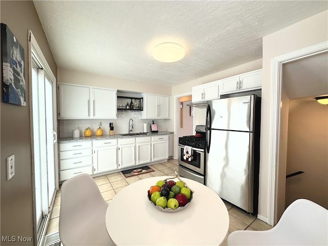 kitchen featuring light tile patterned floors, white cabinetry, appliances with stainless steel finishes, and a sink