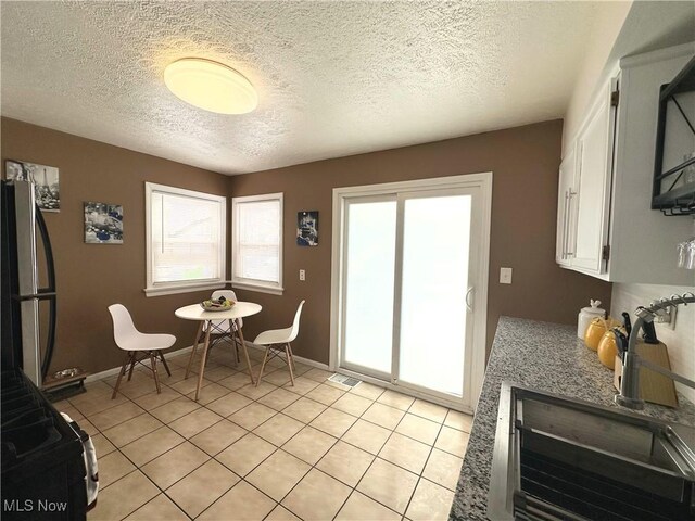 dining room with light tile patterned floors, a textured ceiling, visible vents, and baseboards