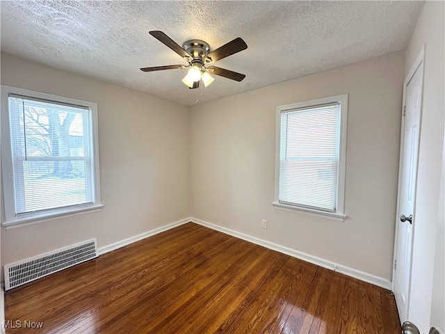 empty room featuring visible vents, ceiling fan, baseboards, and hardwood / wood-style flooring