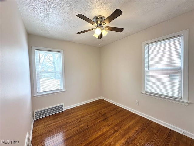 unfurnished room with baseboards, visible vents, a ceiling fan, wood finished floors, and a textured ceiling