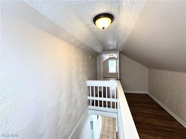 bonus room featuring a textured ceiling, vaulted ceiling, wood finished floors, and baseboards