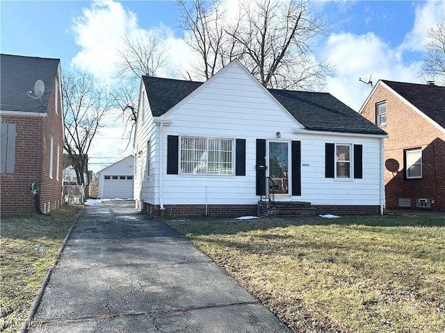 bungalow-style home with an outbuilding, roof with shingles, a detached garage, entry steps, and a front lawn