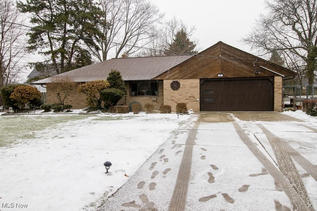 view of front of home with a garage, concrete driveway, and brick siding