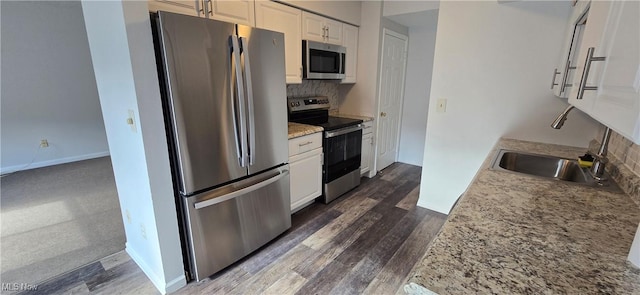 kitchen with stainless steel appliances, baseboards, white cabinets, tasteful backsplash, and dark wood finished floors