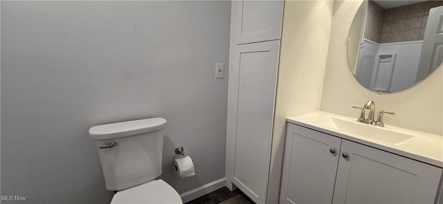 bathroom featuring baseboards, vanity, and toilet