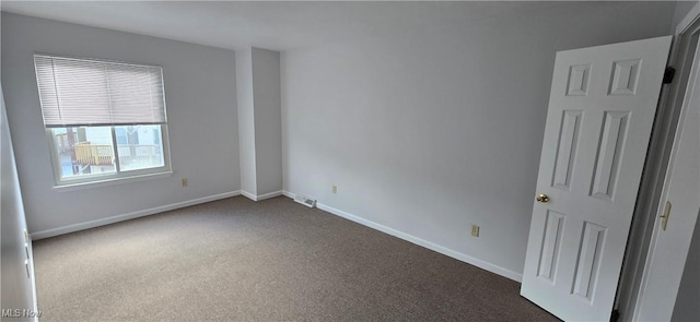 empty room featuring visible vents, dark carpet, and baseboards