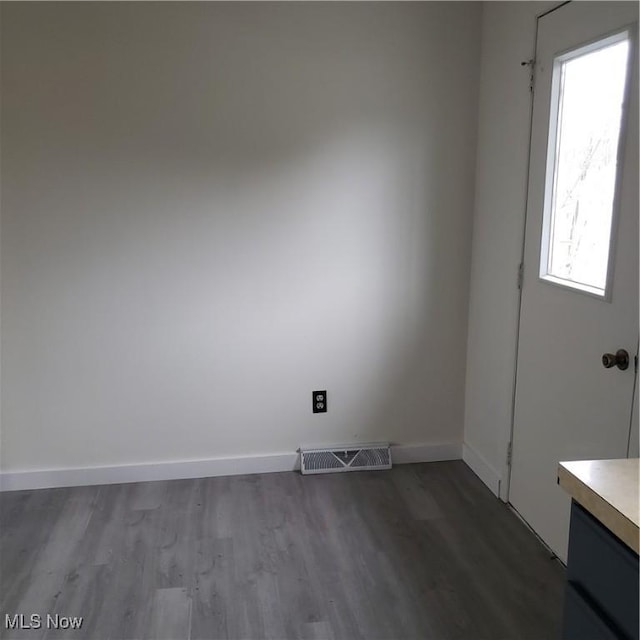 empty room featuring wood finished floors, visible vents, and baseboards