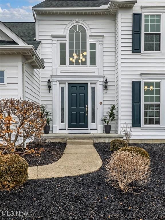 doorway to property with a shingled roof