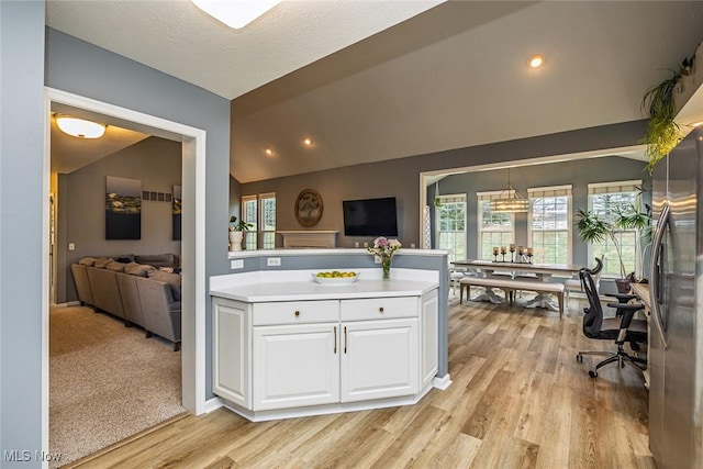 kitchen featuring light wood-style floors, vaulted ceiling, light countertops, white cabinets, and freestanding refrigerator