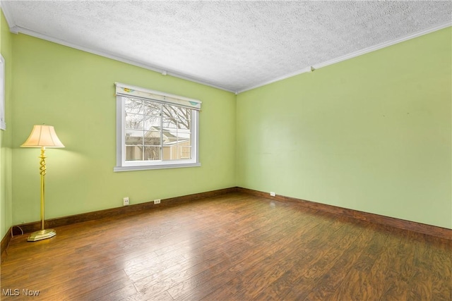 empty room featuring hardwood / wood-style flooring, baseboards, and crown molding