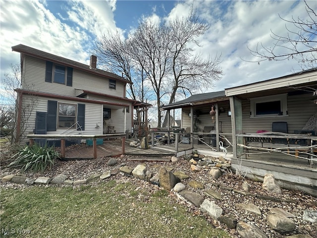 back of house featuring a chimney and a wooden deck