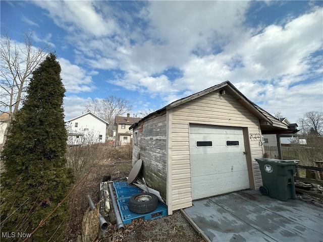 detached garage featuring concrete driveway and fence