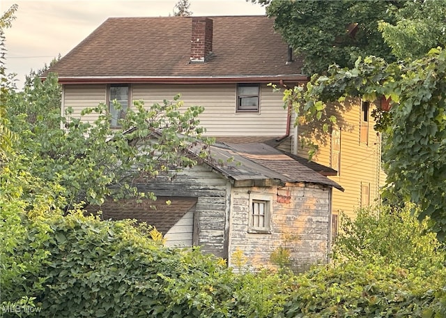 back of property featuring a shingled roof and a chimney