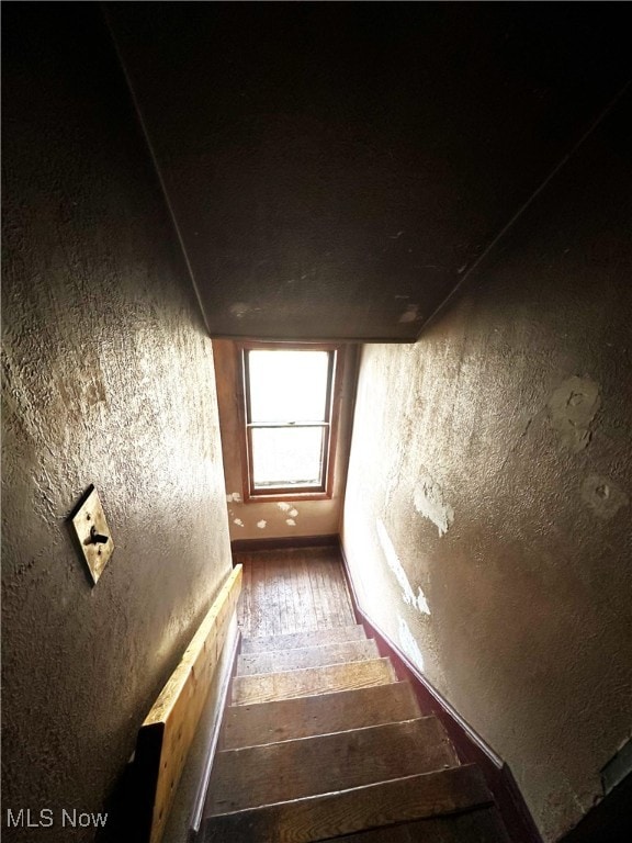 staircase featuring a textured wall and wood-type flooring