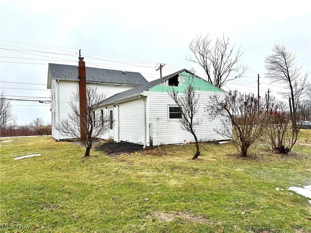 view of property exterior featuring roof with shingles and a yard