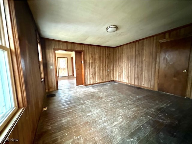 unfurnished room featuring dark wood-type flooring, ornamental molding, and wooden walls