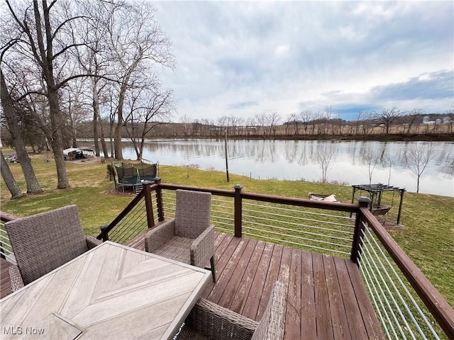 wooden terrace with a water view, a lawn, and a trampoline
