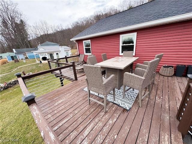 wooden terrace featuring outdoor dining area and a yard