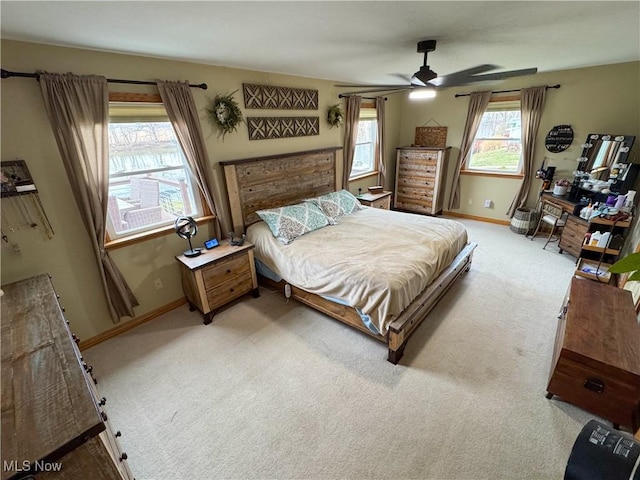 bedroom with a ceiling fan, baseboards, and light carpet