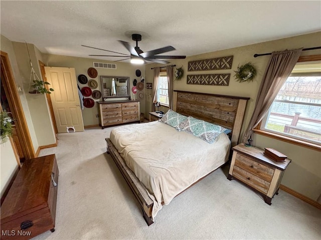 bedroom featuring visible vents, baseboards, ceiling fan, a textured ceiling, and light colored carpet