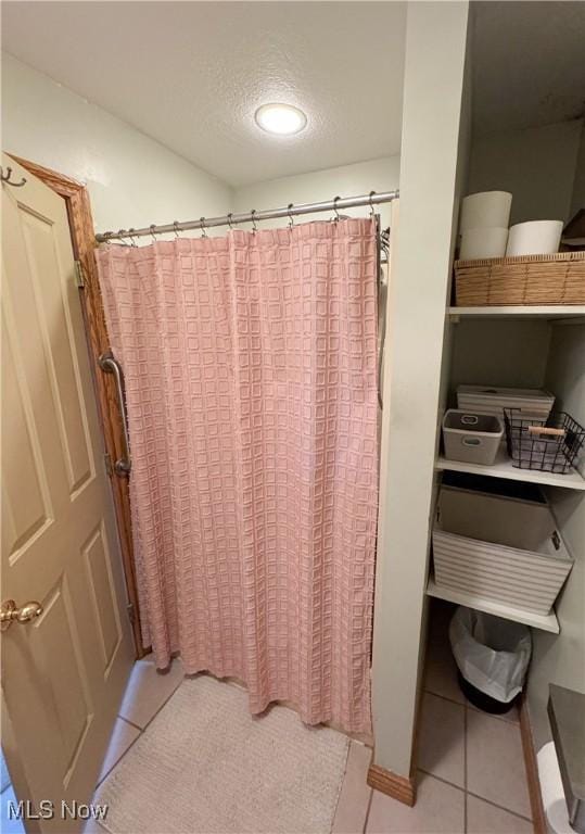 full bathroom featuring tile patterned flooring, curtained shower, and a textured ceiling