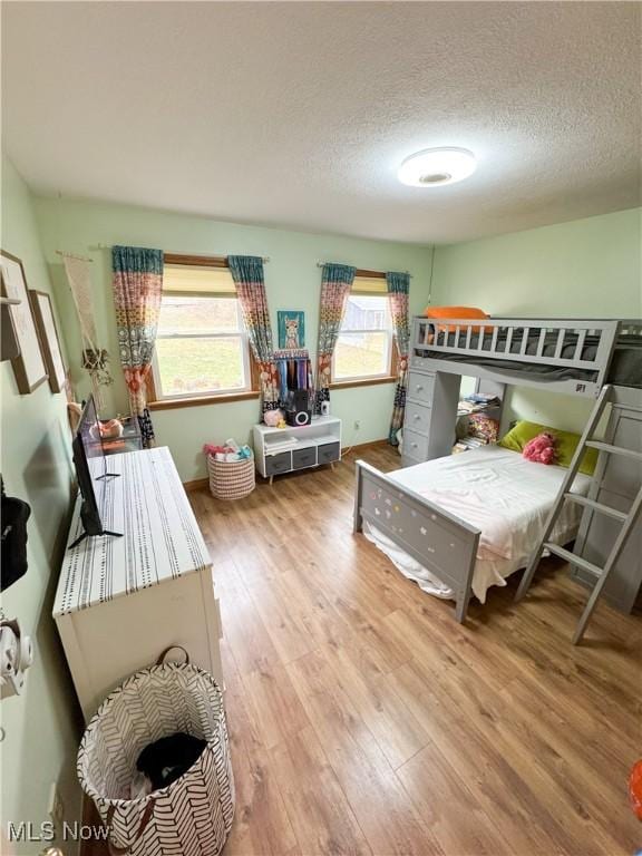 bedroom featuring wood finished floors, baseboards, and a textured ceiling